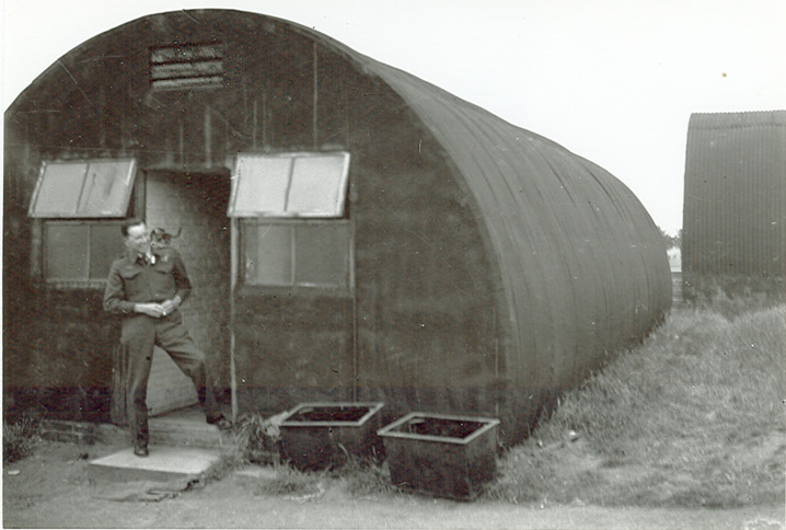 John Y. T. Ogle with pet on his shoulder in front of Nissan Hut